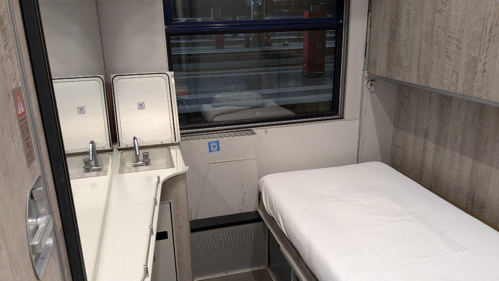 Schlafwagenabteil mit einem Bett und einem kleinen Waschbecken