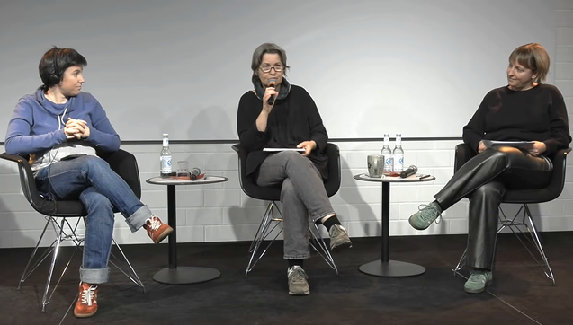 Carmela Troncoso, Anne Roth, Elisa Lindinger sitzen auf einem Podium, zwischen ihnen kleine Tische mit Wasserflaschen. 