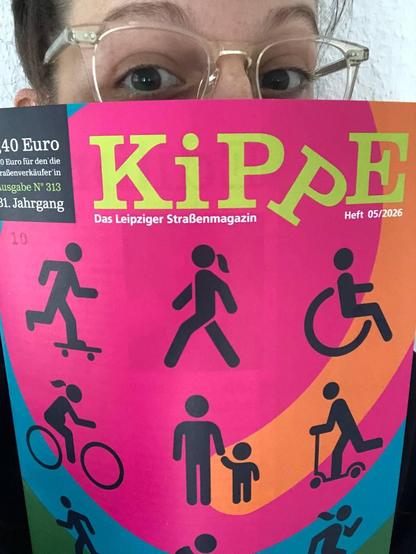 Hinter dem Titelblatt einer Zeitschrift lugt eine weibliche Person mit Brille hervor.